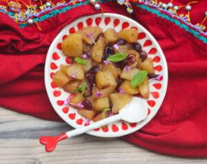 Manzana rehogada con canela y frutas frescas en plato blanco, postre saludable.