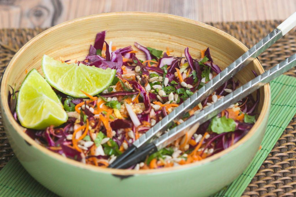 ensalada thai mijo en un bol de madera servida con lima