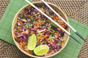 ensalada thai mijo en un bol de madera servida con lima