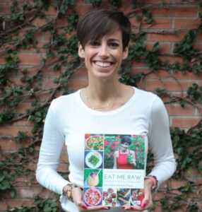 mujer sosteniendo el libro de recetas Programa Crudivegano 21 días Eat Me Raw de la Dra. Carlota Esteve de Miguel