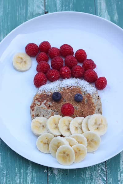 pancake con cara de papá noel, el gorro es de frambuesas y la barba de plátano