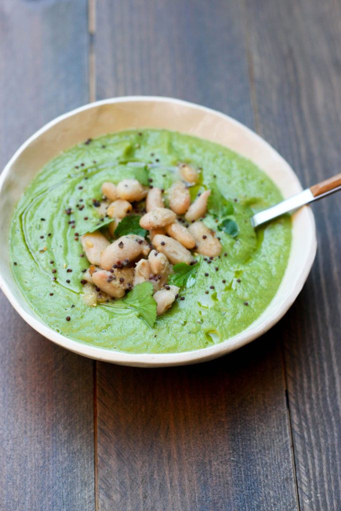 crema vegetal verde con habas blancas por encima servida en un bol blanco