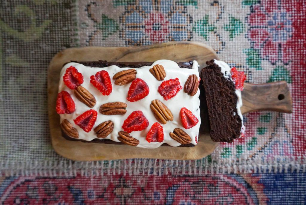 pastel de chocolate con salsa blanca de vainilla y frambuesas y nueces pecanas por encima