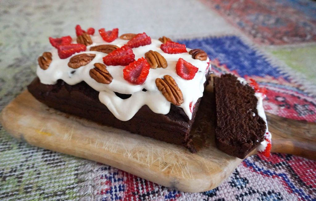 pastel de chocolate con salsa blanca de vainilla y frambuesas y nueces pecanas por encima