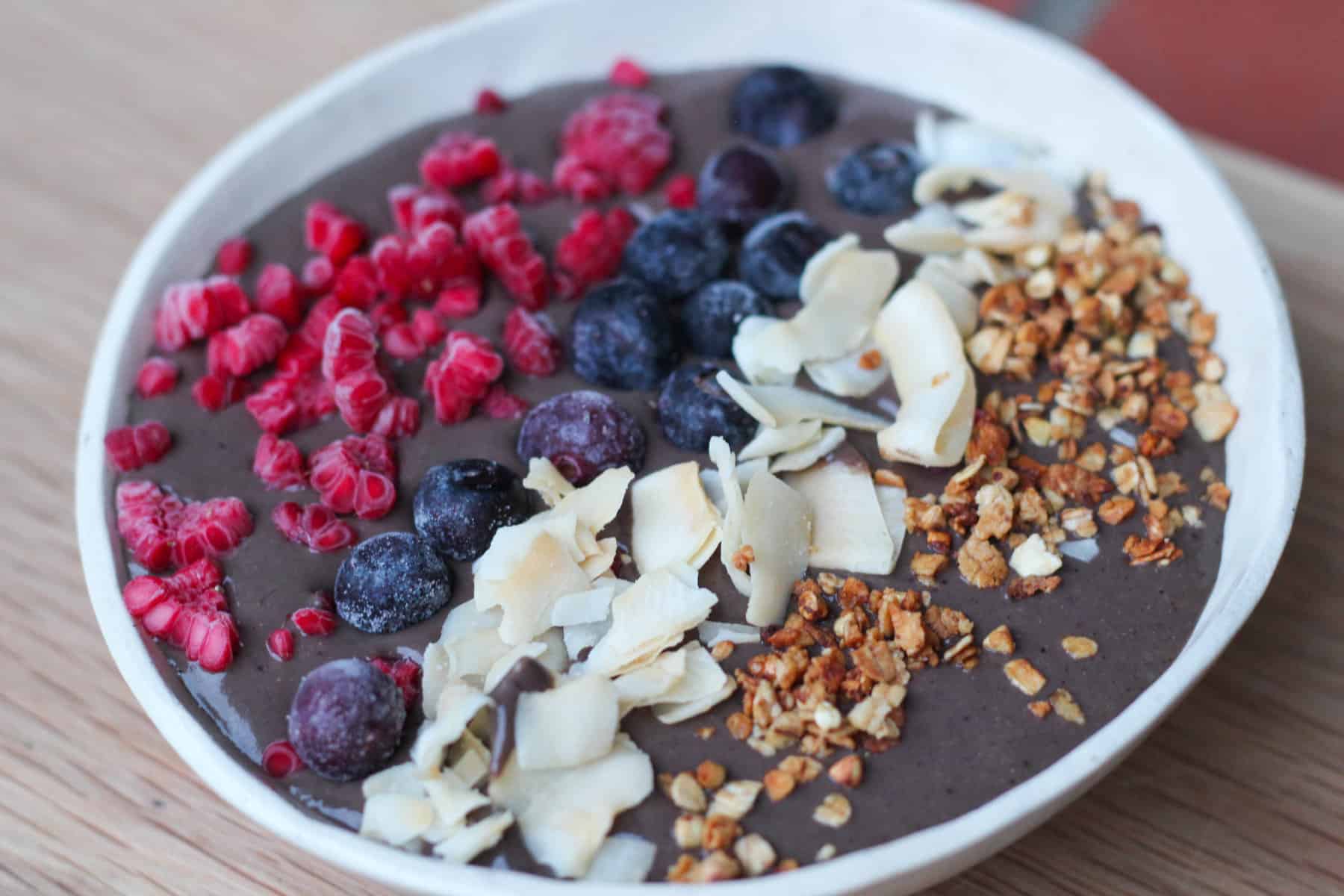 batido de arándanos en un bol, con coco, frutos rojos y granola
