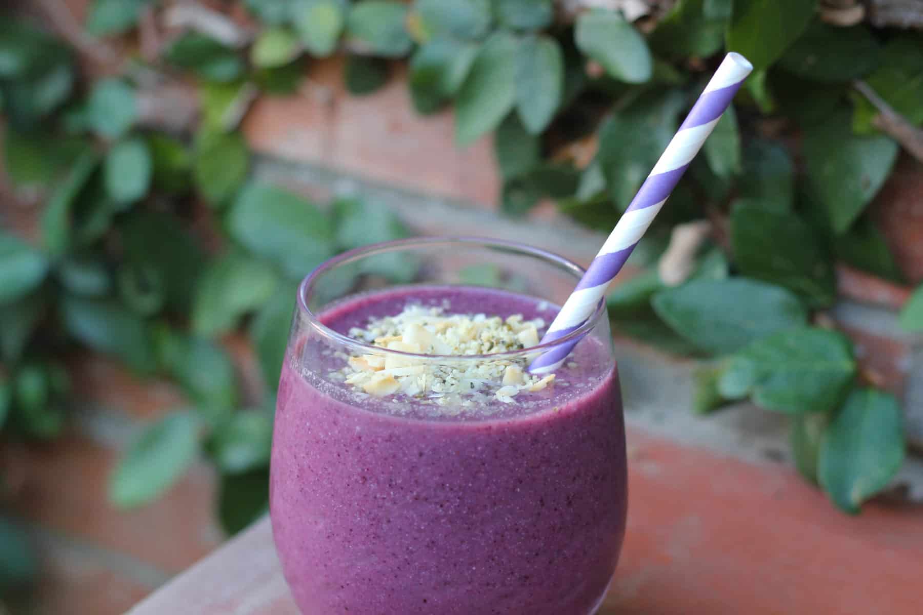 batido de arándanos en un vaso de cristal y pajita