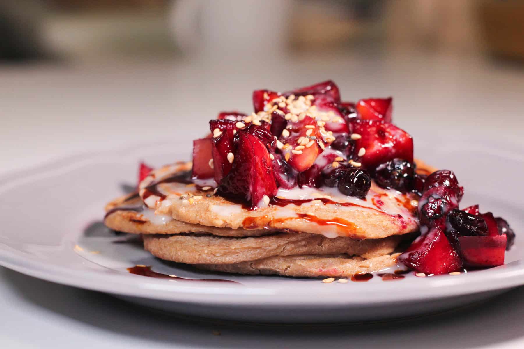 tortitas servidas en un plato con salsa de frutos rojos