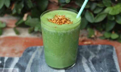 batido verde en un vaso de cristal y una pajita
