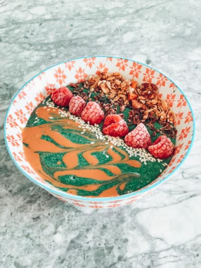 Batido verde en un bol con frambuesas y semillas