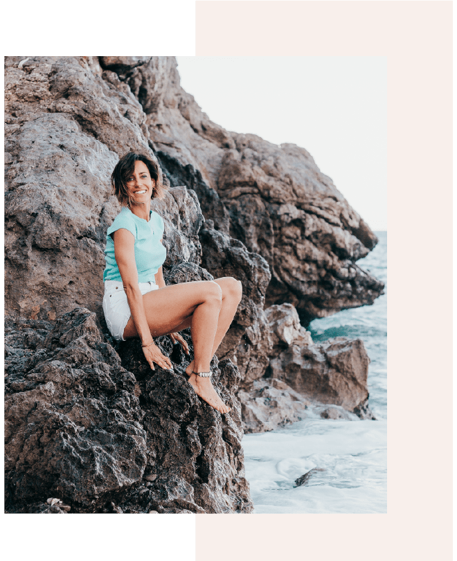 mujer sentada en una roca a la orilla del mar