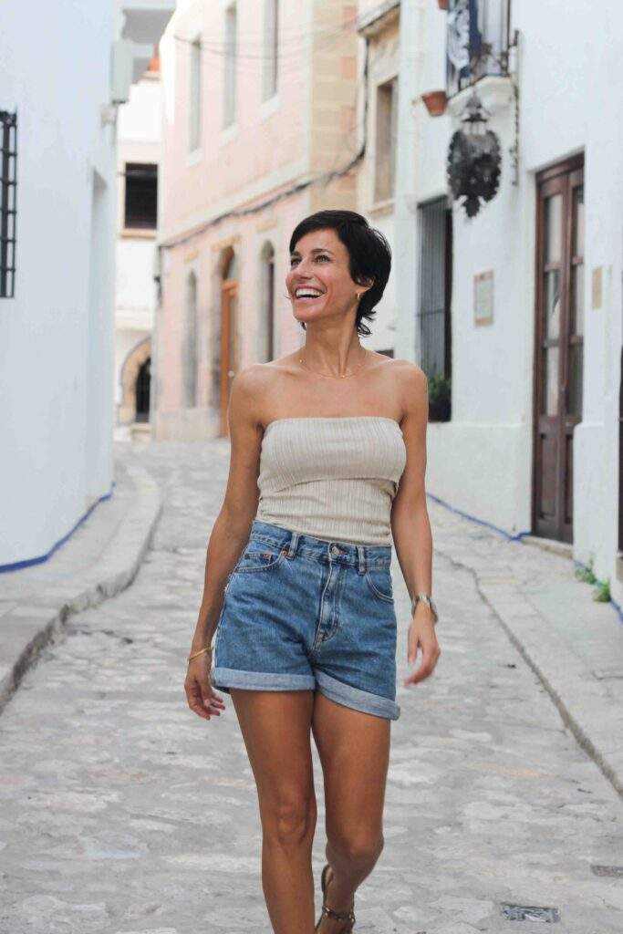 Mujer caminando por calle empedrada vestida con ropa veraniega