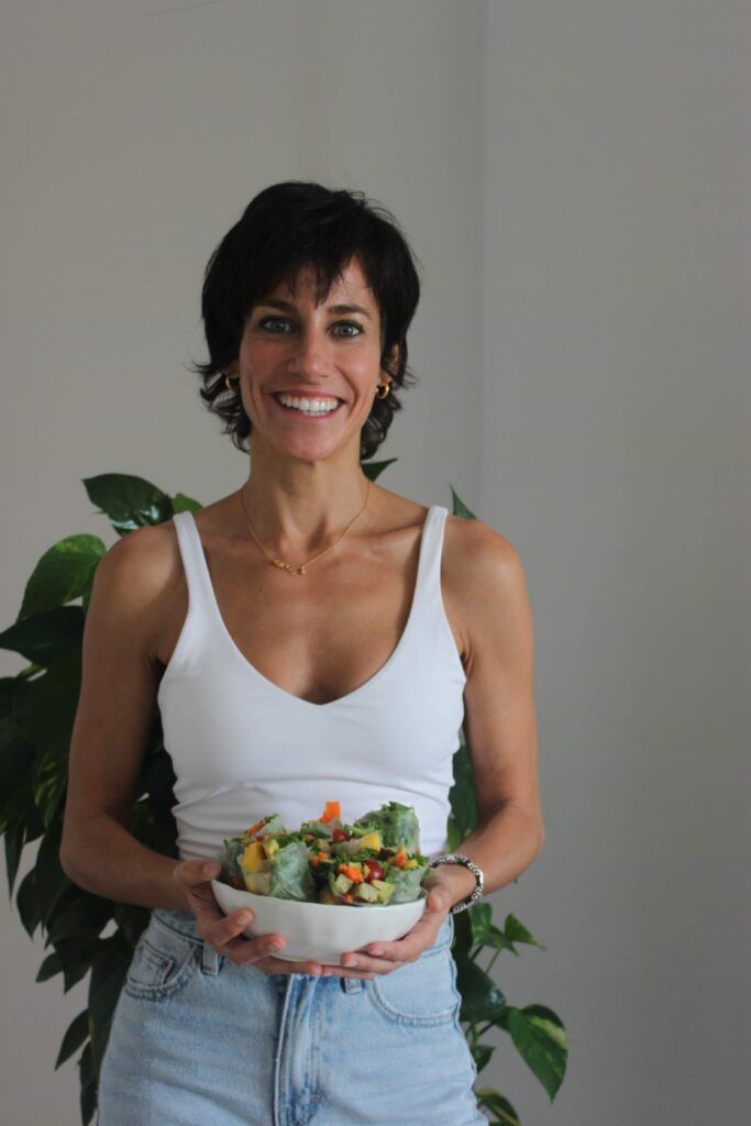 Mujer sosteniendo un bol de ensalada fresca en la cocina