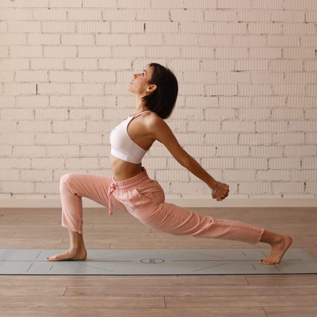 Mujer practicando una postura de yoga en un estudio luminoso.