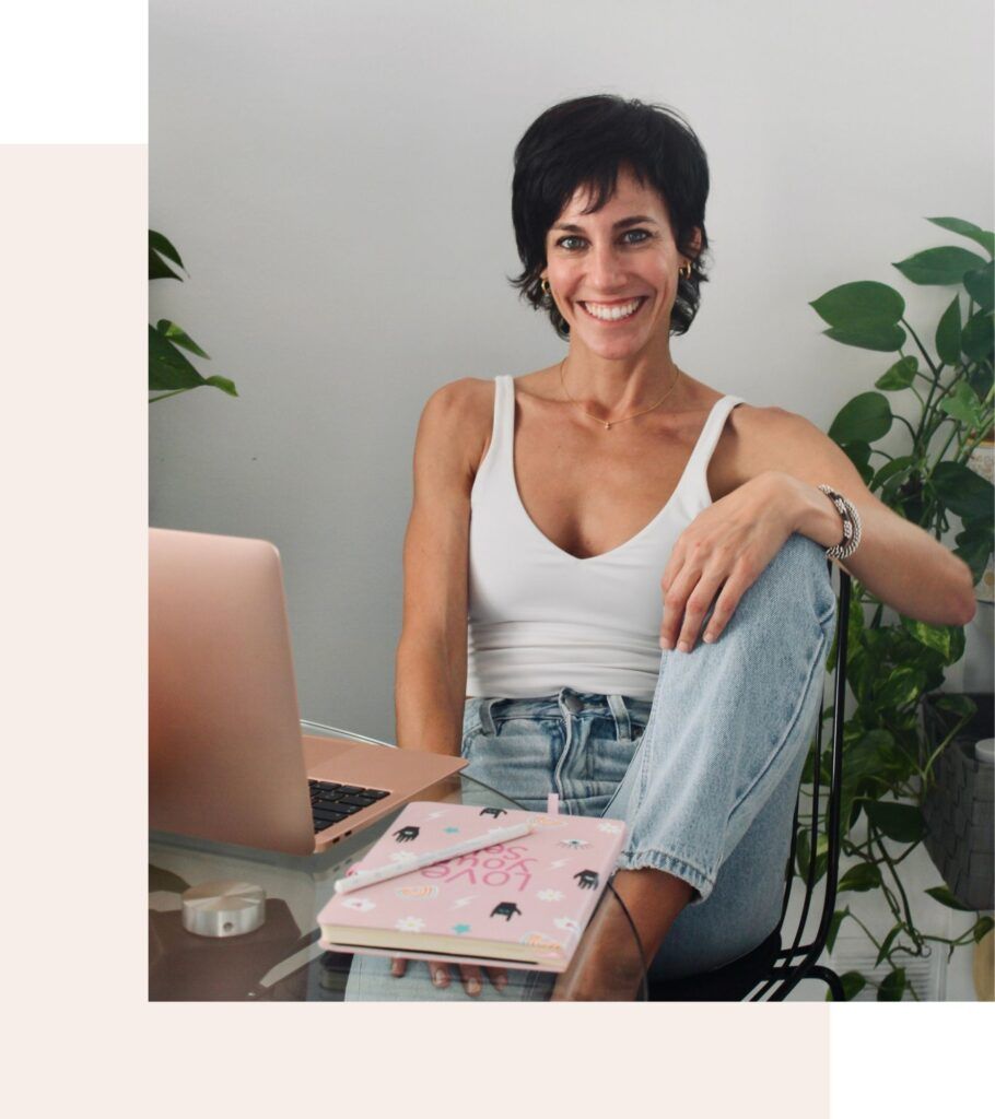 Mujer sentada con un portátil y un cuaderno, sonriendo en un ambiente natural