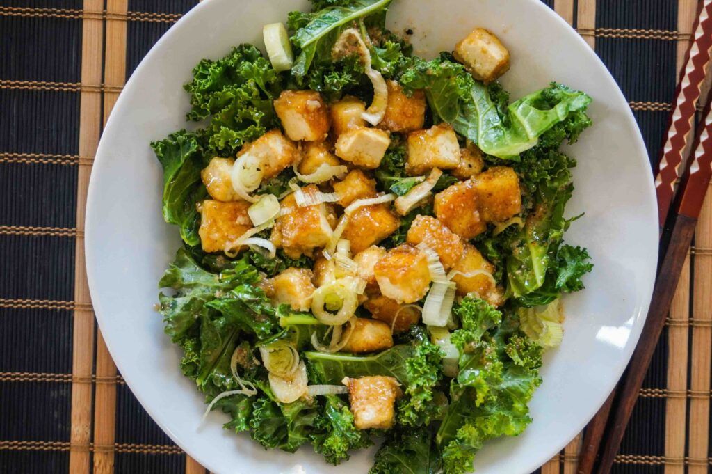 Plato de tofu agridulce servido con kale y verduras frescas